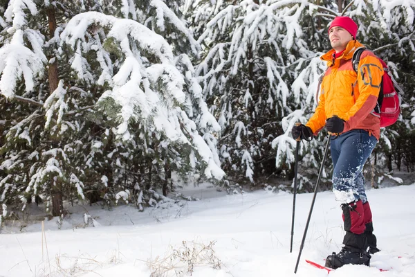 Um homem caminhando na neve com uma mochila . — Fotografia de Stock