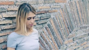 Bir duvara yaslanmış sıkılmış ve yalnız kız: üzücü, üzüntü, düşünceli