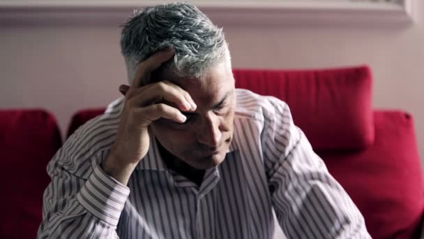 Beautiful man sitting on his sofa thinking about problems: sad, alone, thoughts — Stock Video