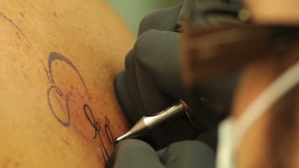 Tatoo's artist draws a black  F on man's back — Stock Video