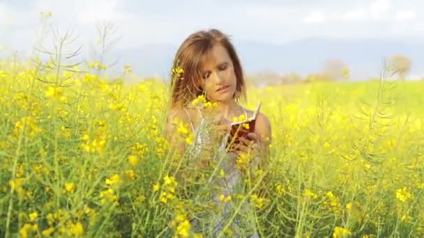 Menina em um campo de estupro amarelo — Vídeo de Stock