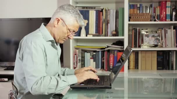 ผู้ชายที่เขียนที่คอมพิวเตอร์ในบ้านของเขา: โต๊ะกระจกเทคโนโลยีเว็บแล็ปท็อป — วีดีโอสต็อก