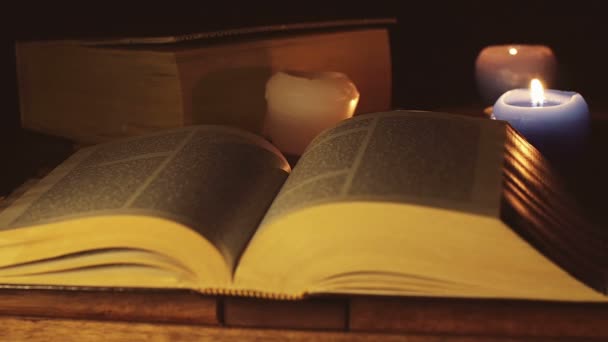 Clear old book opened near burning candle — Stock Video