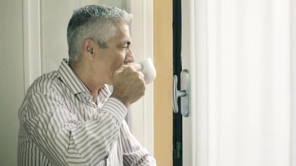 Nachdenklicher Mann, der am Fenster heißen Tee trinkt: Kaffee, Getränk, dampfen, gucken — Stockvideo