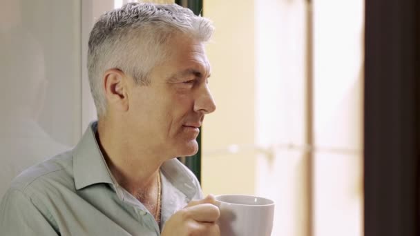 Knappe man buiten kijken naar het venster warme koffie drinken — Stockvideo