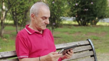 dinlenme ve park masasında onun tablet kullanarak emekli kıdemli adamı