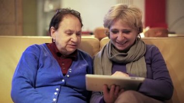 Annesi bir tablet Pc veren ve onu kullanmak için öğretim yetişkin kadın