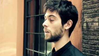 Dalgın guy duvara yaslanmış ve birini bekliyor ve sigara içmek