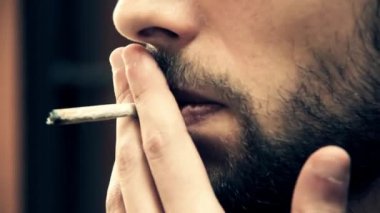 Dalgın guy duvara yaslanmış ve birini bekliyor ve sigara içmek