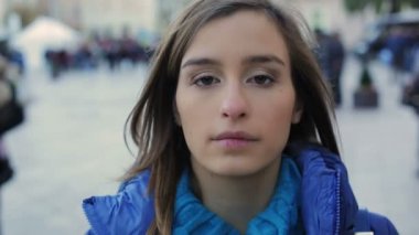 Kız akşam şehir merkezindeki mavi montlu. Kameraya bakıyor. Slowmotion