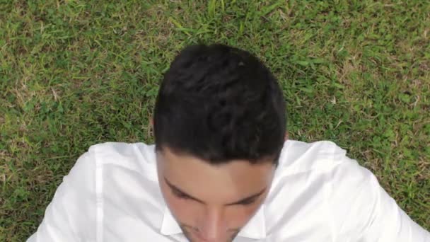 Young business man lying on grass and relaxing in green park — Stock Video