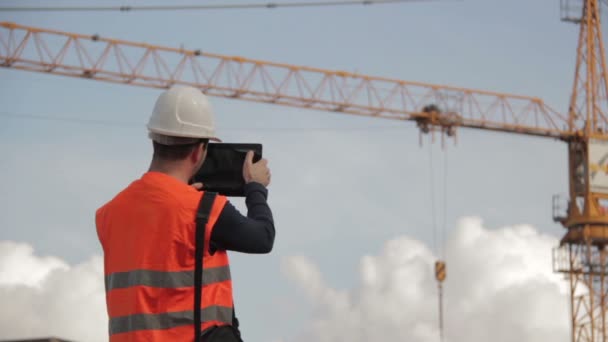 Ingeniero de construcción con chaleco de seguridad con grúa amarilla en el fondo nosotros — Vídeos de Stock