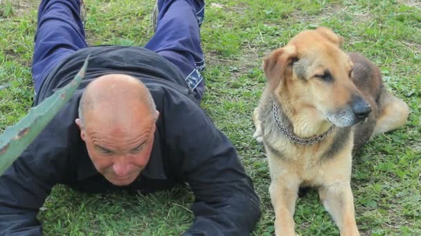 Uomo sdraiato sull'erba con il suo cane — Video Stock