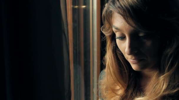 Красивая грустная девушка скучает по окну — стоковое видео