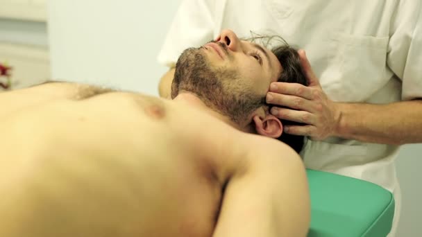 Physiotherapist is examining the patient's pain points: head, neck, mouth, jaw — ストック動画