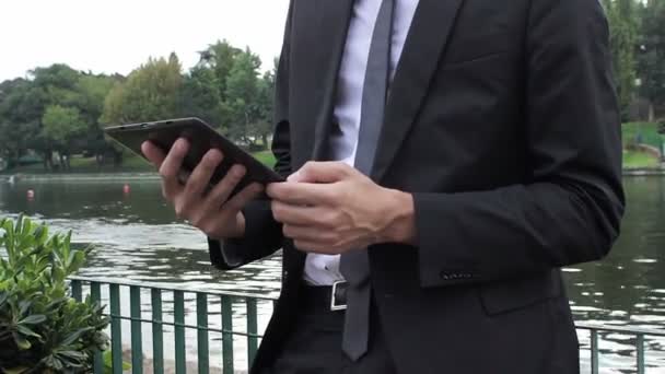 Άνθρωπος των επιχειρήσεων χρησιμοποιεί ψηφιακή δισκίο στο πάρκο — Αρχείο Βίντεο