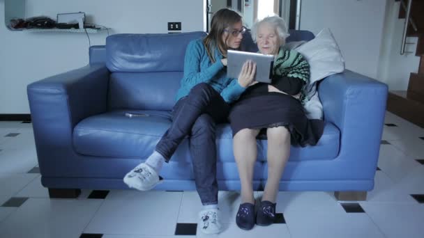 Jeune femme donnant à sa grand-mère une tablette PC et lui apprenant à l'utiliser — Video