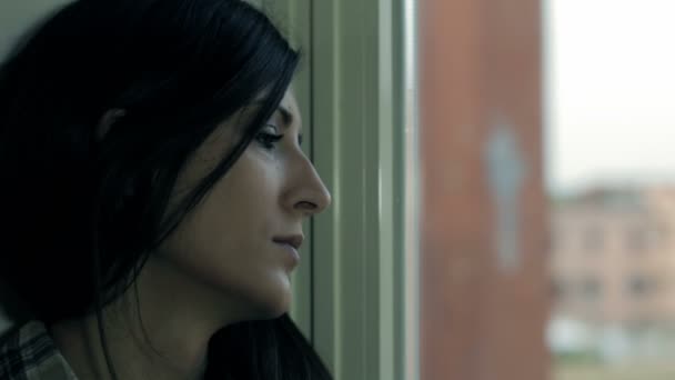 Сумна дівчина біля вікна думає про щось — стокове відео