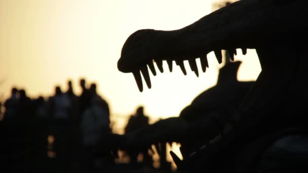 Perfil de dinosaurios en un parque de atracciones al atardecer — Vídeos de Stock