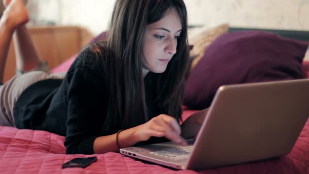 Porträtt av vacker brunett kvinna med laptop på sängen i sovrummet — Stockvideo