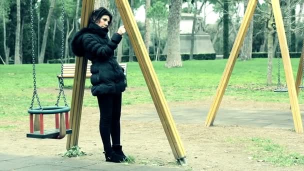 女性が公園でブランコ近く傾いています。 — ストック動画