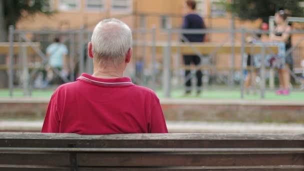 Einsame und traurige alte Männer auf einer Bank mit dem Rücken zur Wand — Stockvideo