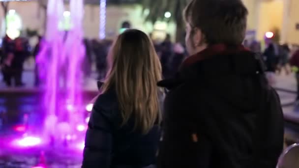 Beautiful smiling couple meeting in front of a fountain at night — Stockvideo