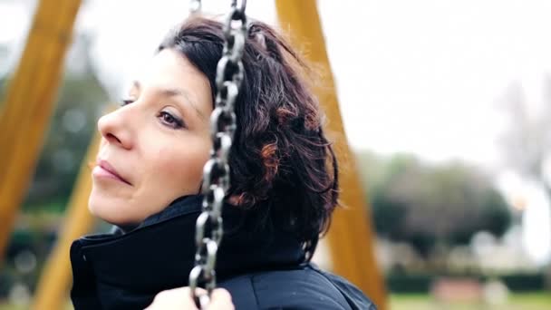 Депрессивная девушка на качелях в осеннем парке — стоковое видео