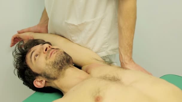 Tratamiento del dolor de hombro: joven, paciente, hombre, mesa de examen, clínica — Vídeos de Stock