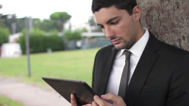 Hombre de negocios debajo del árbol usando tableta — Vídeo de stock