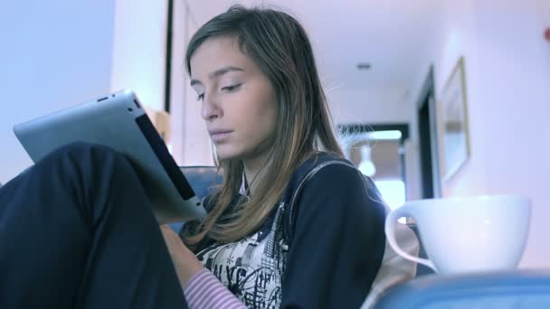 Улыбающаяся молодая женщина с помощью планшетного компьютера дома по утрам — стоковое видео
