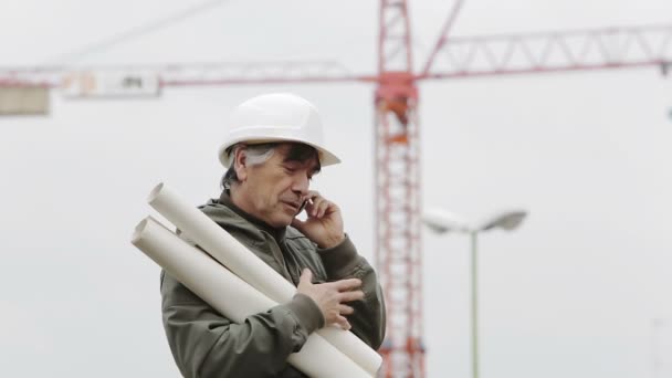 Инженер в шлеме разговаривает со смартфоном — стоковое видео