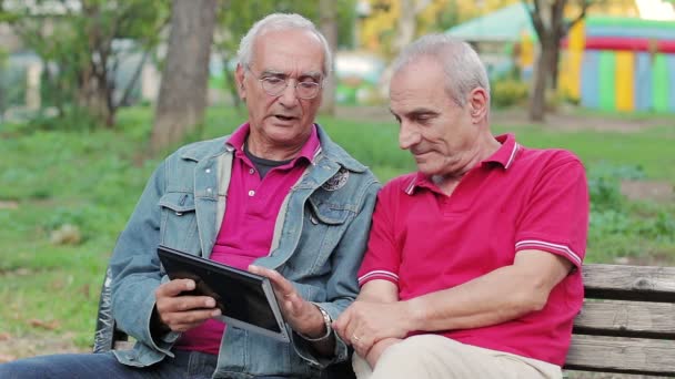 Anciano enseñando a sus viejos amigos a usar una nueva tableta PC — Vídeos de Stock