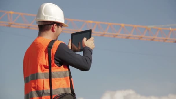 Bauingenieur trägt Warnweste mit gelbem Kran im Hintergrund — Stockvideo
