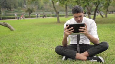 Tablet kullanarak ağacın altında oturup iş adamı