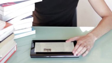 Genç adam bir tablet ile masa üzerinde kitap yığını üzerinde eğitim