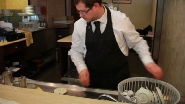 Bulaşık makinesinde yemekleri yükleyerek barda barmen çalışıyor