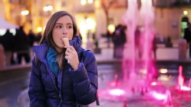 Dondurma ile bir sokakta oturan genç güzellik kadın. Arka plan üzerinde çeşme