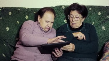 Emeklilik maaşı alan iki yaşlı kadın tablet bilgisayarlı.