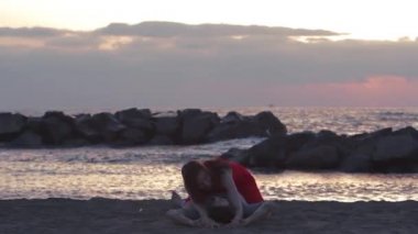 Genç çift sahilde öpüşüyor.