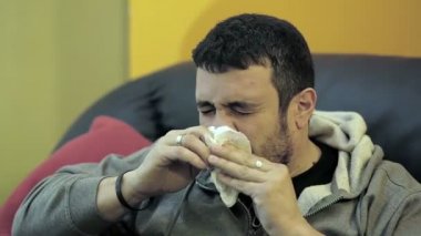 hasta bir adam kanepede hapşırma: soğuk, mendil, hastalık. burun silin