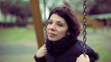 Sonbahar parkta bir salıncak üzerinde depresif kız