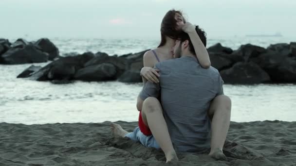 Молодая пара целуется на пляже — стоковое видео