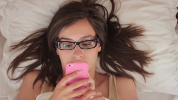 Giovane bella donna utilizzando sul letto e tenendo smartphone — Video Stock