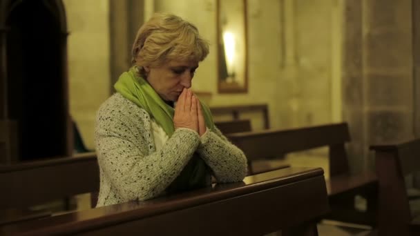 Портрет белокурой женщины, молящейся в церкви — стоковое видео