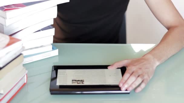 Hombre joven estudiando en una pila de libros en el escritorio con la tableta — Vídeos de Stock