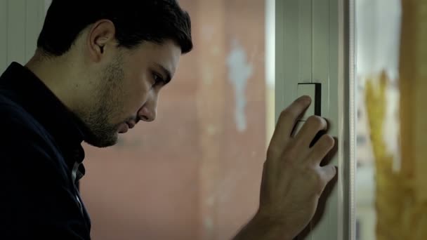 Portrait of young worried man looking through window — Stock Video