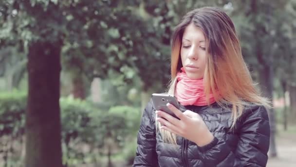 Γυναίκα που χρησιμοποιούν κινητό τηλέφωνο στο πάρκο — Αρχείο Βίντεο