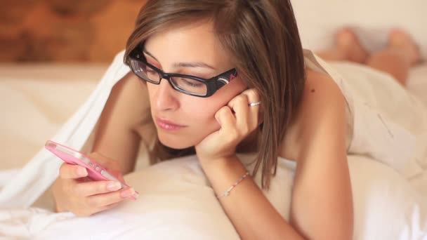 Jeune belle femme utilisant sur le lit et tenant smartphone — Video