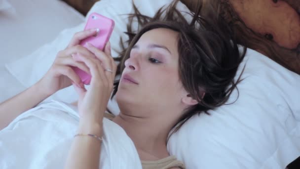 Жінка використовує смартфон у ліжку — стокове відео